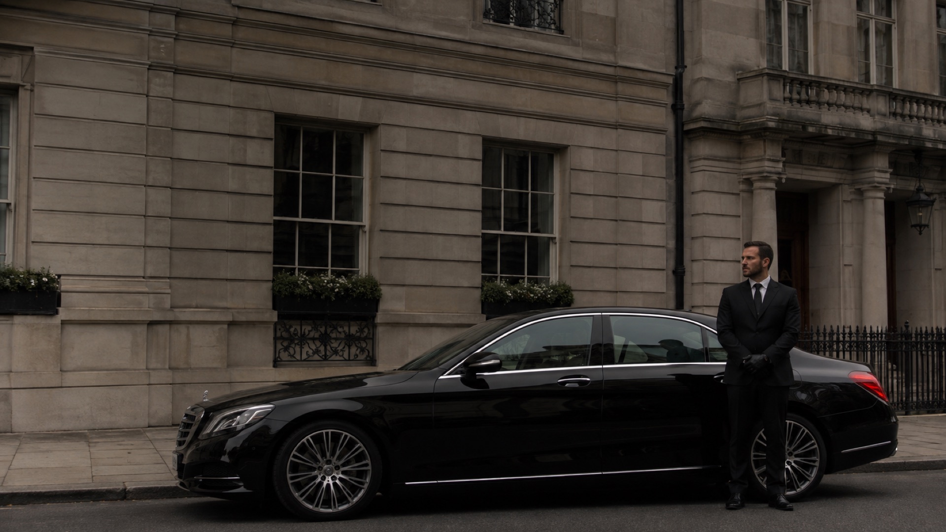 Illustration of a chauffeur beside a black saloon on a London street