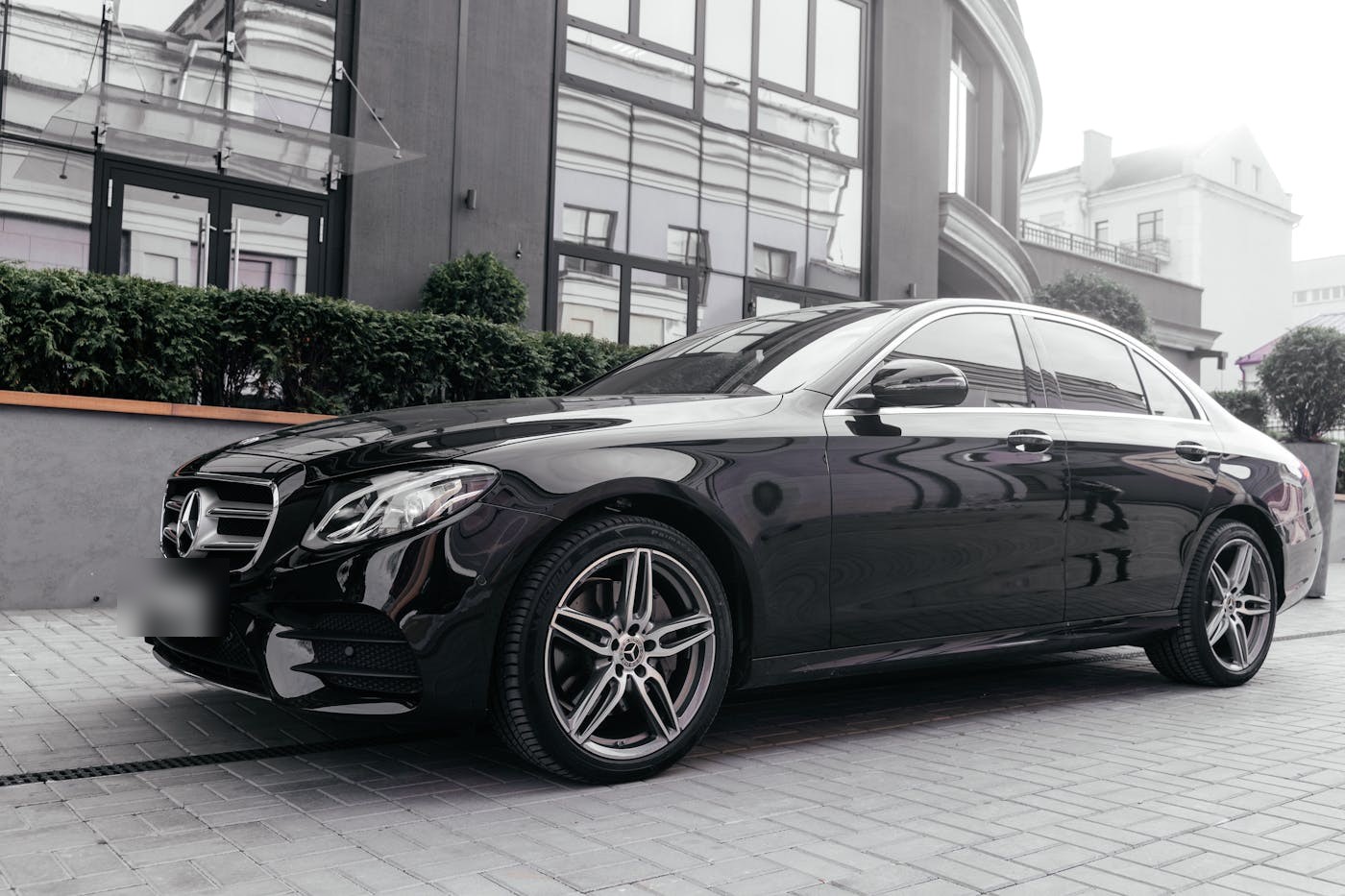 Black Mercedes-Benz E-Class outside a modern hotel