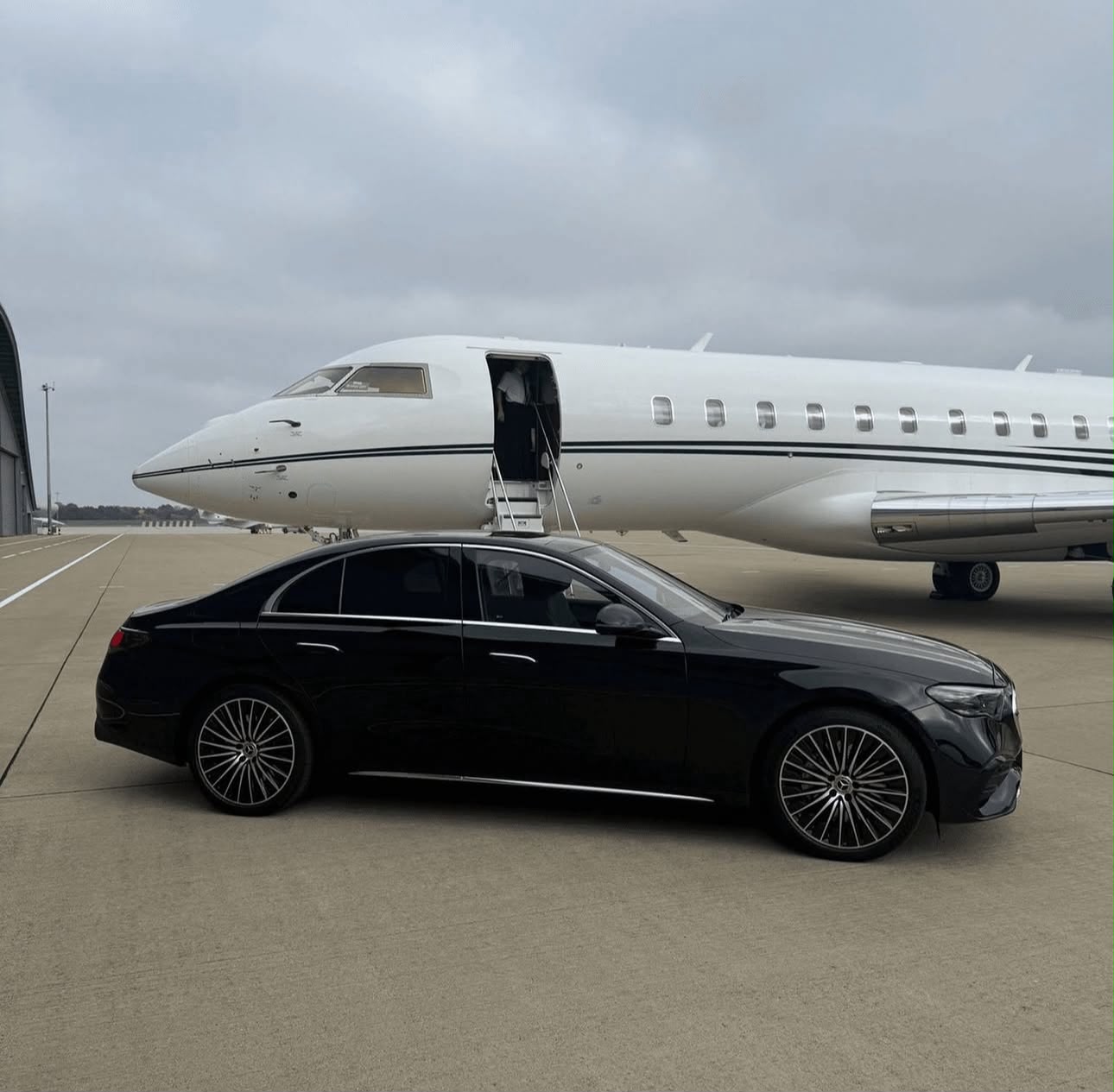 Black Mercedes-Benz E-Class beside a private aircraft